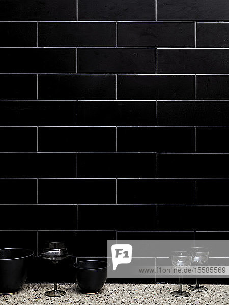 Wine glasses and bowls beside tiled wall