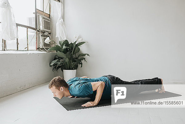 Mann macht halbe Planke im Yoga-Studio