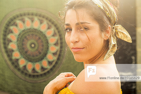 Young woman in headscarf looking over her shoulder at community garden party  head and shoulders portrait