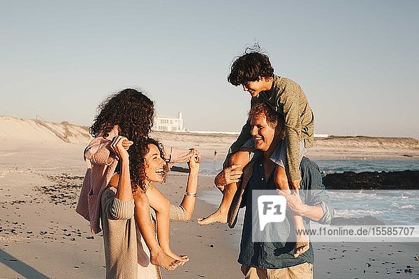Couple giving children piggyback ride on beach