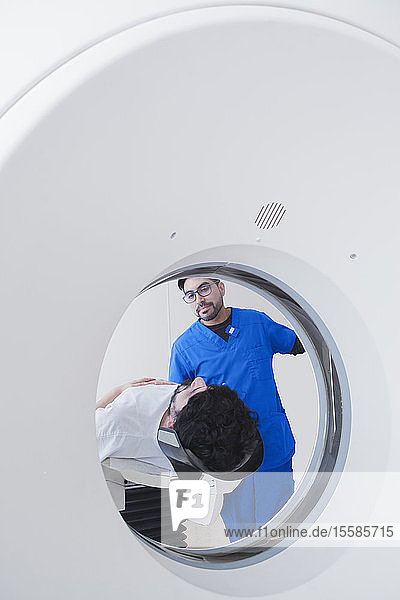 Junger männlicher Radiologe am operativen CT-Scanner in der radiologischen Abteilung