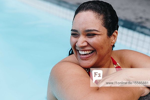 Mittelgroße erwachsene Frau mit nassem Haar lehnt am Swimmingpool im Freien und schaut über ihre Schulter  Kapstadt  Südafrika