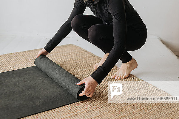 Frau rollt Yogamatte im Studio
