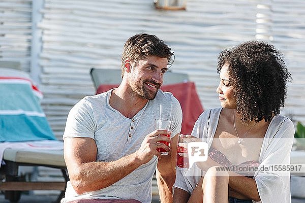 Ehepaar genießt eisgekühltes Getränk am Schwimmbad