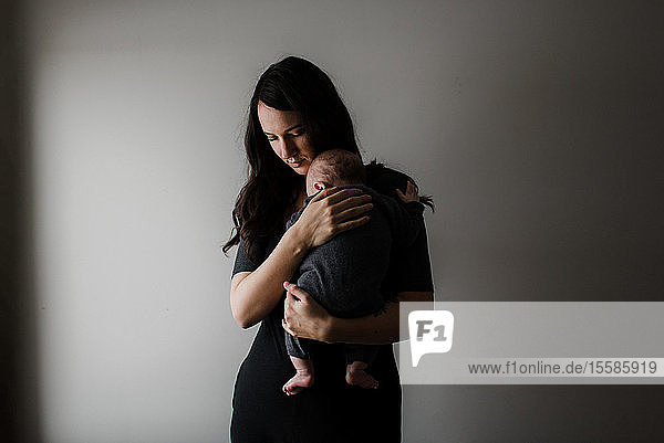 Young woman carrying baby son in arms low key