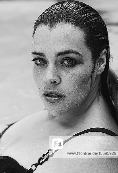 Sultry mid adult woman with wet hair leaning against outdoor swimming poolside  black and white head and shoulder portrait  Cape Town  South Africa