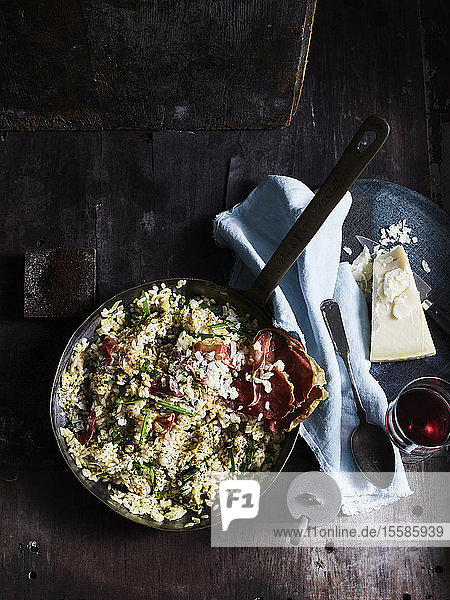 Rustic low key still life with skillet of risotto capers and espresso on table overhead view
