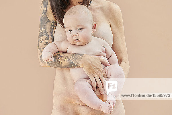Nackte Mutter trägt nacktes Baby auf dem Arm