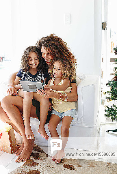Mutter und Töchter benutzen digitales Tablett zu Hause