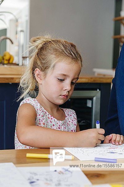 Little girl colouring picture at home