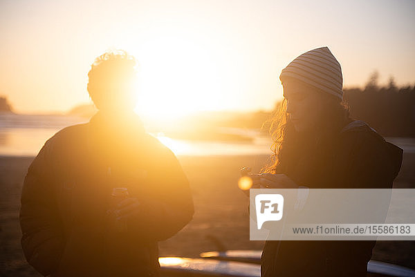 Zwei Freundinnen im mittleren Erwachsenenalter an der Küste bei Sonnenuntergang Tofino Vancouver Island Kanada