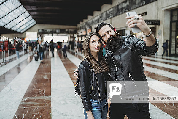 Paar  das sich mit einem Smartphone am Bahnhof selbstständig macht