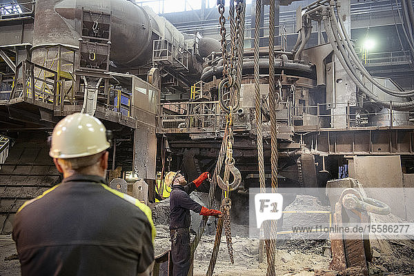 Workers arranging crane lines in steelworks