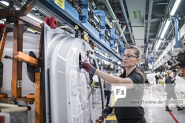 Arbeitnehmerin bei der Montage von Autotüren am Fließband in einer Autofabrik