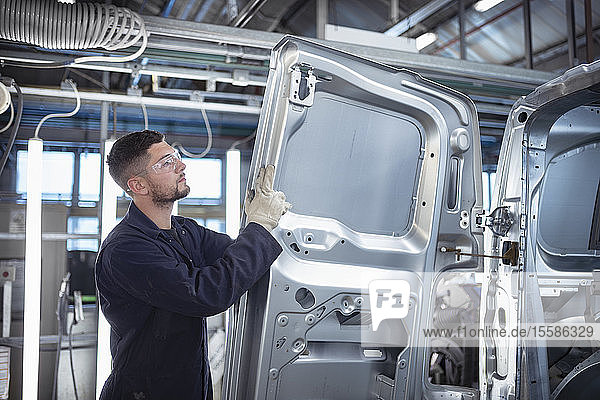 Worker inspecting car body in car factory