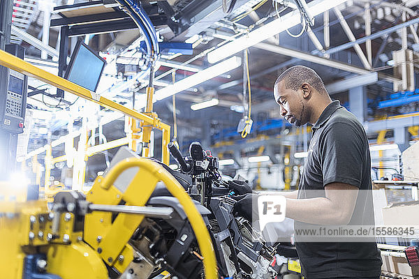 Worker assembling dashboard on production line in car factory