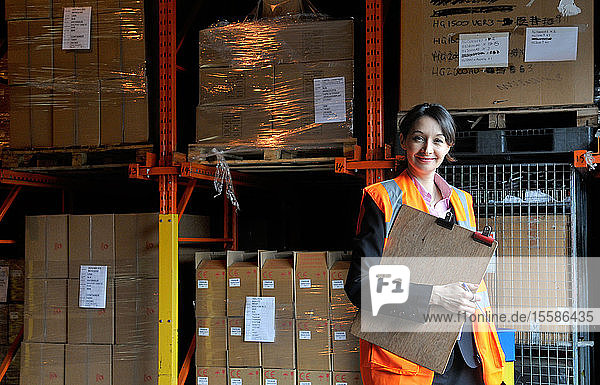 Young female factory worker with clipboard in warehouse  portrait