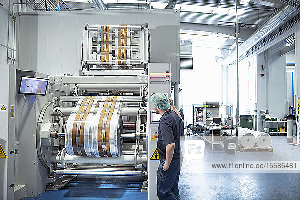Worker with food packaging printing machine in print factory