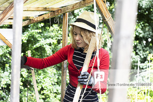 Mittlere erwachsene Frau  die in ihrem Garten eine Holzhütte baut