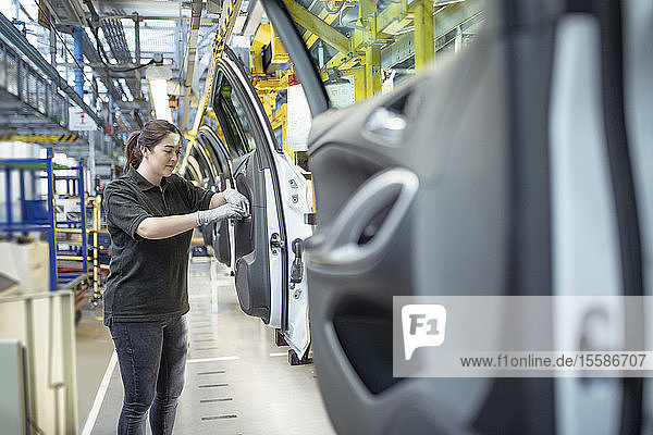 Female apprentice engineer assembling car doors in car factory