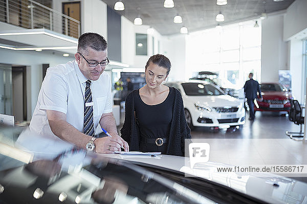 Salesman showing literature to customer in car dealership