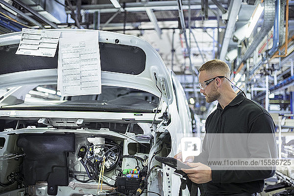 Engineer with digital tablet on production line in car factory
