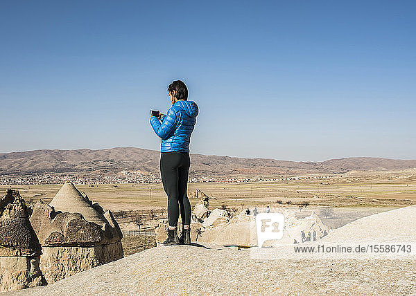 Woman taking photograph of fairy chimney  GÃ¶reme  Cappadocia  Nevsehir  Turkey