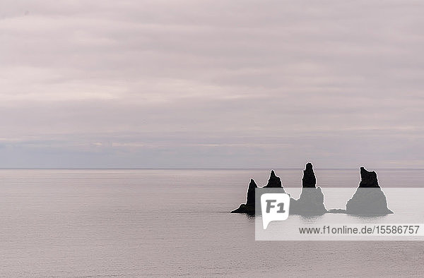Meereslandschaft mit einer Reihe zerklüfteter Felsformationen und bedecktem Himmel Reynisdrangar Vik Island