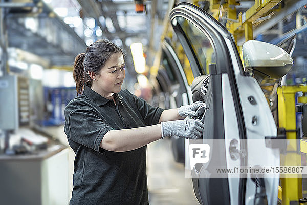 Female apprentice engineer assembling car doors in car factory