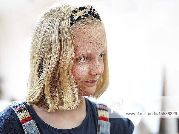 Mädchen mit Sommersprossen und blondem gebauschtem Haar  wegblickend  Kopf und Schulterporträt
