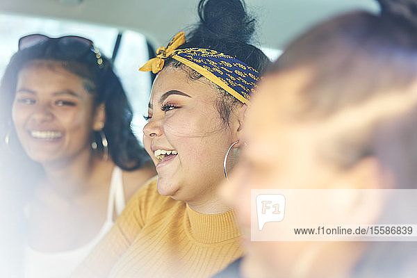 Junge Frau mit jugendlichen Schwestern auf dem Rücksitz im Auto lachend  Nahaufnahme