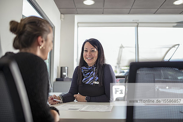 Saleswoman talking to customer in car dealership