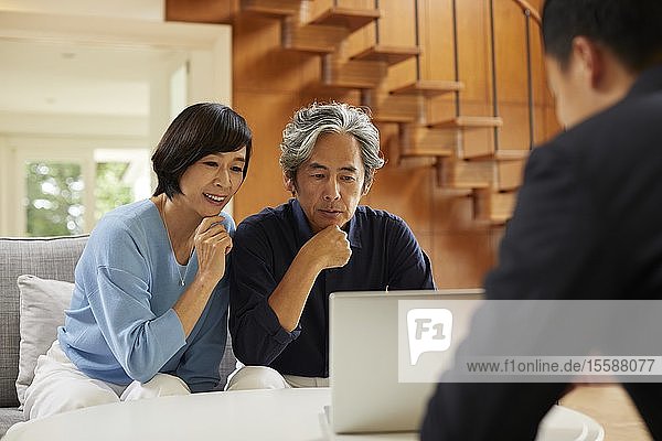 Senior Japanese couple at home with salesman