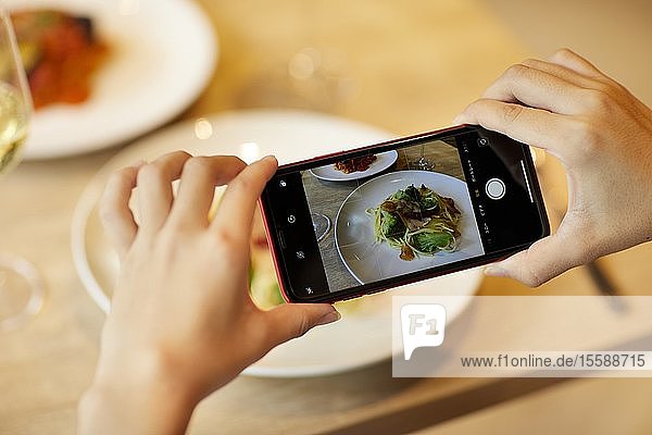 Frau fotografiert Essen in einem Restaurant