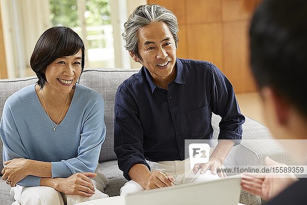 Senior Japanese couple at home with salesman