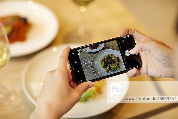 Frau fotografiert Essen in einem Restaurant