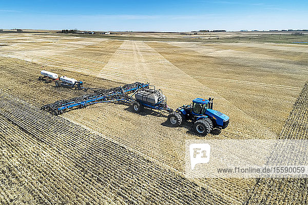Air seeder in field with white ammonia tanks  near Beiseker; Alberta  Canada