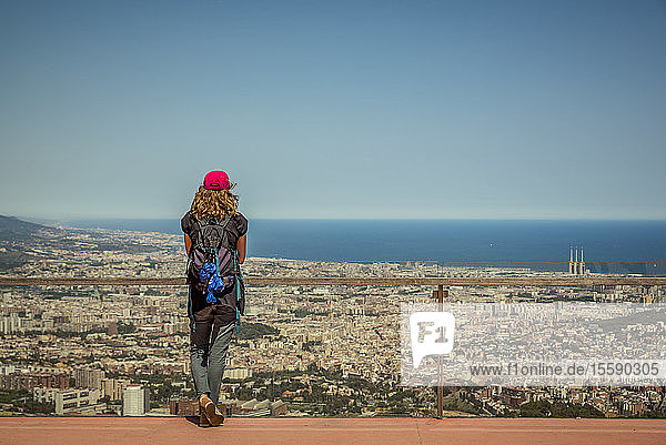 Tourist steht an einem Geländer im Tibidabo-Vergnügungspark mit Blick auf die Stadt Barcelona und das Mittelmeer; Barcelona  Katalonien  Spanien