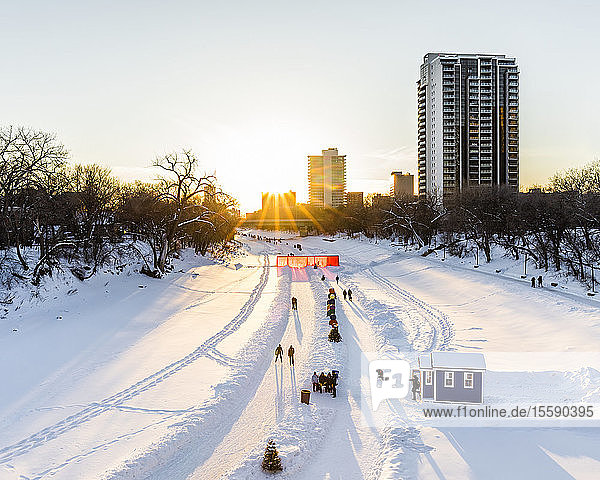 Ice skating at sunset on the Assiniboine River part of the Red River Mutual Trail at The Forks; Winnipeg Manitoba Canada