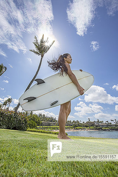 A young woman with surfboard at Kapalua Bay and beach; Maui  Hawaii  United States of America