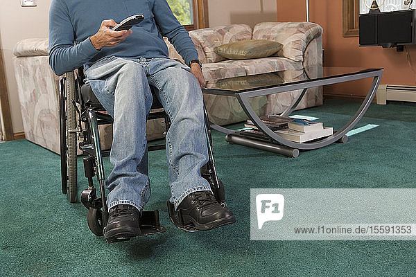 Mann mit Rückenmarksverletzung im Rollstuhl  der eine Fernsteuerung benutzt
