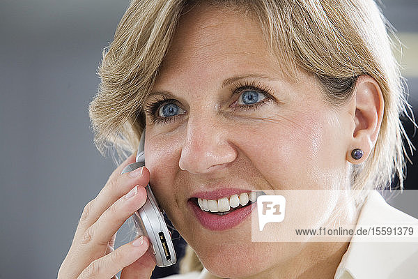 Eine lächelnde Geschäftsfrau  die ein Mobiltelefon benutzt.
