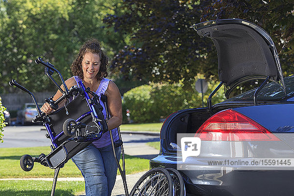 Frau mit Spina Bifida nimmt Rollstuhl auseinander  um ihn hinten im Auto zu verstauen