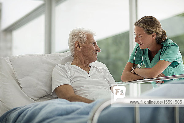 Porträt eines älteren Mannes in einem Krankenhausbett und einer jungen Ärztin