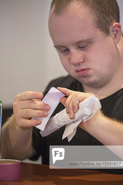 Waiter with Down Syndrome preparing napkin and silver in a restaurant