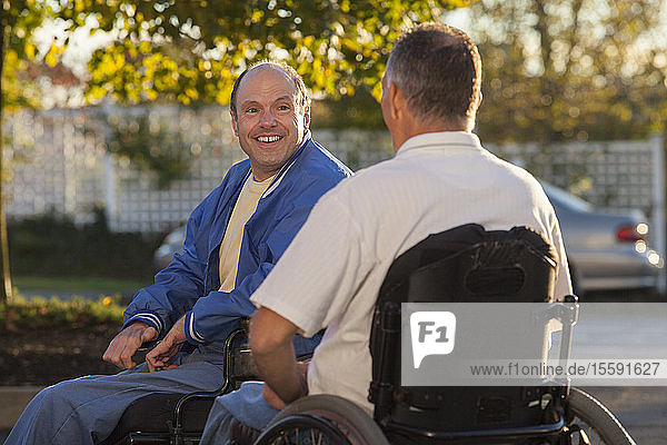 Mann mit Friedreich-Ataxie begrüßt seinen Freund mit Rückenmarksverletzung