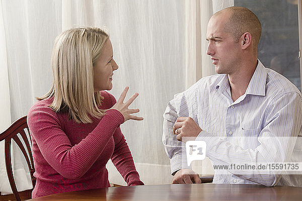Frau gebärdet das Wort Fine in amerikanischer Zeichensprache  während sie mit einem Mann kommuniziert