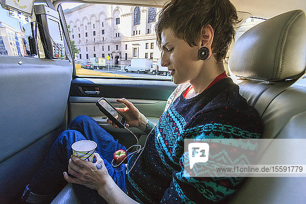 Trendy man with a spinal cord injury in wheelchair inside a taxi cab reading his text messages