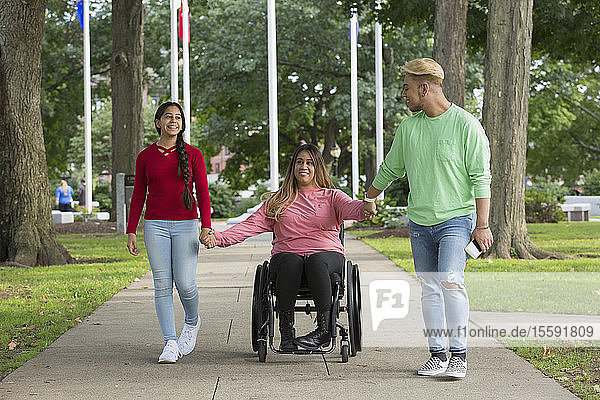 Frau mit Rückenmarksverletzung geht mit Geschwistern im Park spazieren