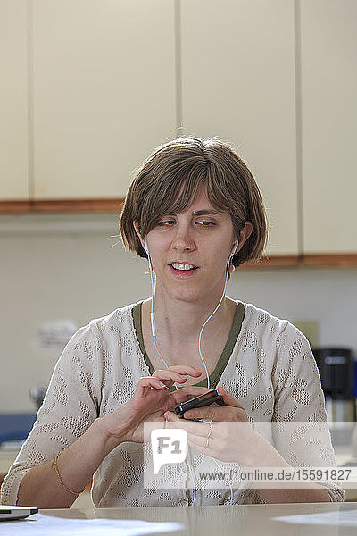 Eine blinde Frau benutzt Ohrstöpsel  um ihr Mobiltelefon zu hören